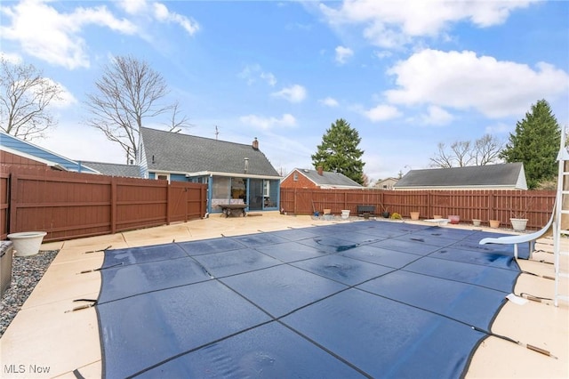 view of pool with a fenced backyard, a water slide, a fenced in pool, and a patio