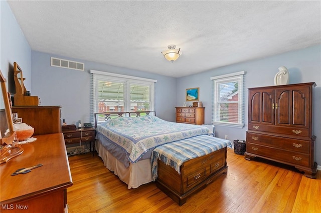 bedroom featuring a textured ceiling, light wood-style flooring, and visible vents