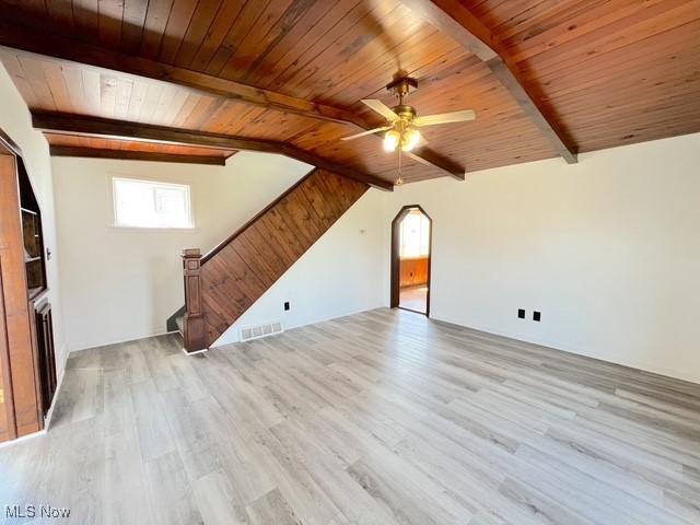 unfurnished living room featuring vaulted ceiling with beams, a ceiling fan, wood finished floors, stairs, and wood ceiling