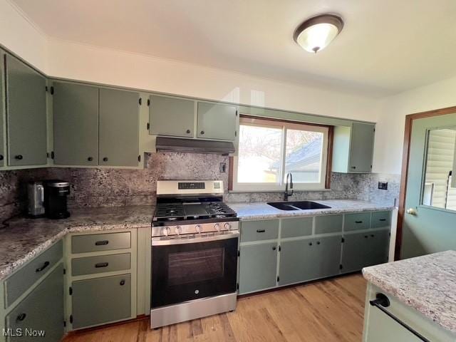 kitchen featuring a sink, stainless steel gas range, plenty of natural light, decorative backsplash, and under cabinet range hood