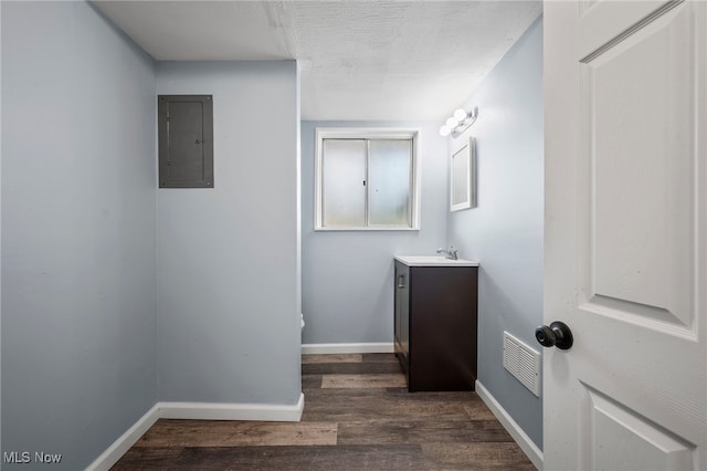bathroom with electric panel, visible vents, baseboards, wood finished floors, and vanity