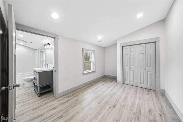 unfurnished bedroom featuring baseboards, vaulted ceiling, and light wood-type flooring