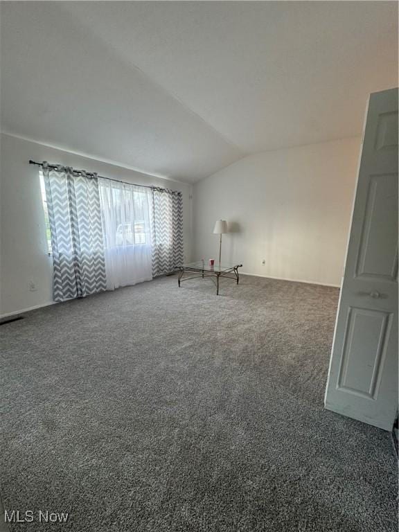 spare room featuring lofted ceiling, visible vents, and carpet