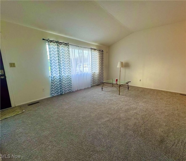 unfurnished room featuring lofted ceiling, visible vents, carpet flooring, and baseboards