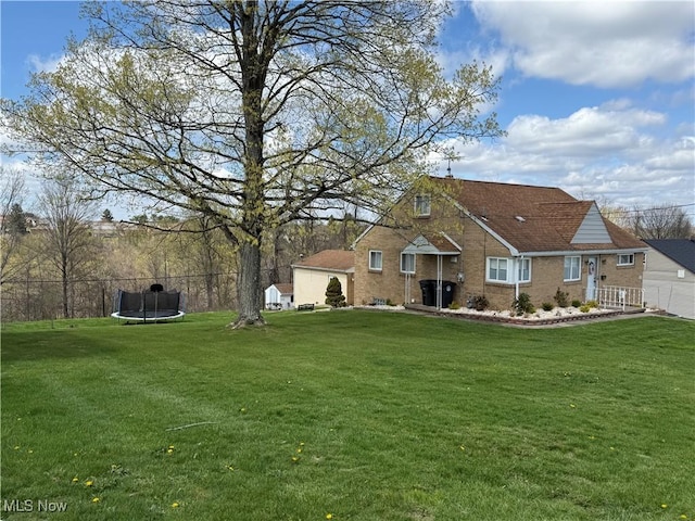 view of front of house with brick siding, a front yard, and a trampoline