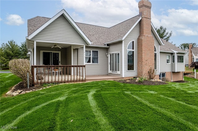 rear view of property with ceiling fan, a lawn, a chimney, and a patio area