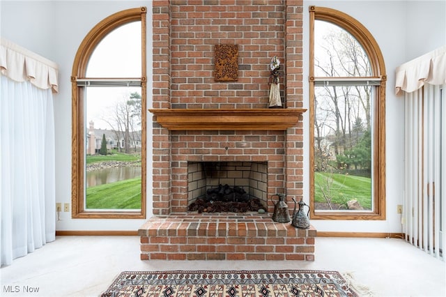 unfurnished living room with a fireplace, baseboards, carpet floors, and a water view