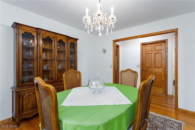 dining room featuring baseboards, wood finished floors, and a chandelier