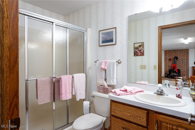 full bathroom featuring wallpapered walls, a shower stall, a wood stove, and vanity