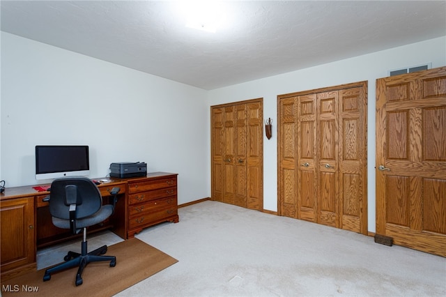 carpeted office space with visible vents and baseboards