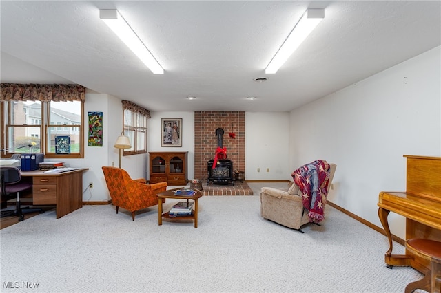 sitting room featuring baseboards, visible vents, a wood stove, and carpet floors