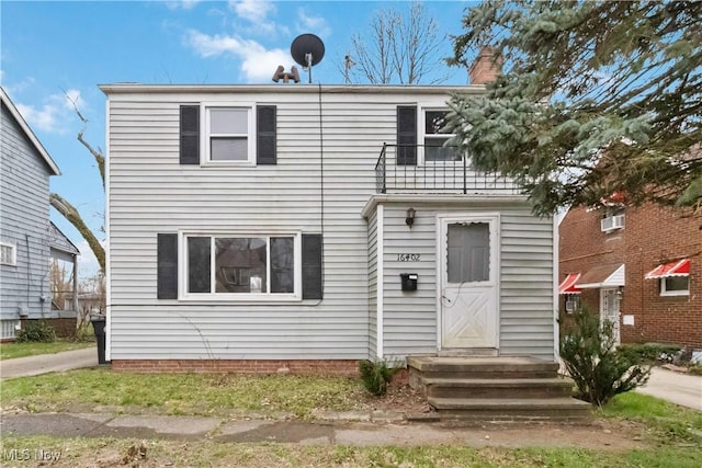 view of front of house featuring a chimney and a balcony