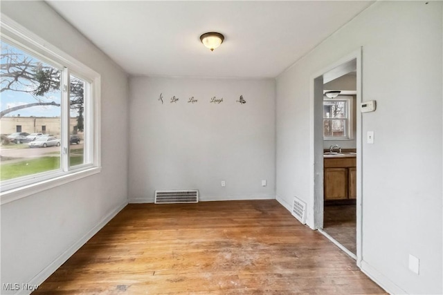 unfurnished dining area with light wood-type flooring, visible vents, and a wealth of natural light