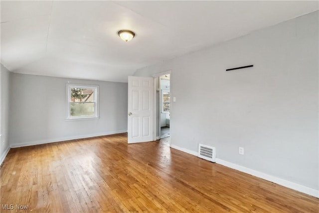 unfurnished room featuring light wood-style floors, visible vents, and baseboards