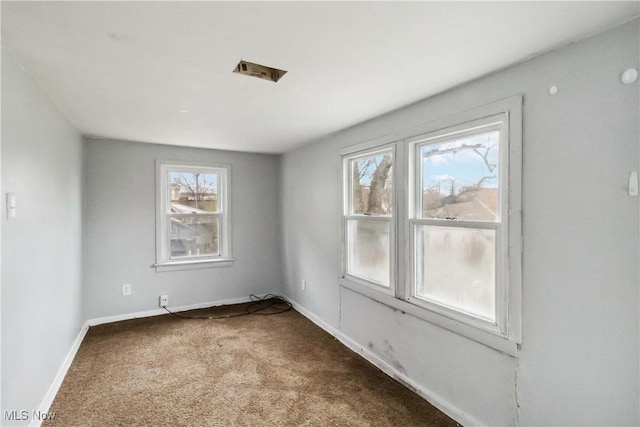 spare room featuring baseboards, carpet flooring, and a wealth of natural light