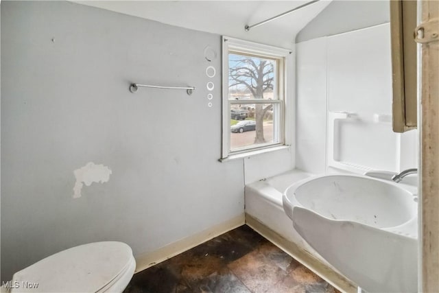 bathroom with baseboards, toilet, and lofted ceiling