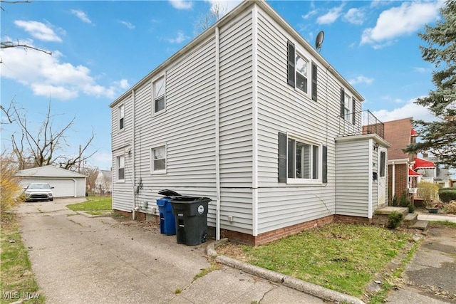 view of side of home featuring an outdoor structure, a balcony, and a garage