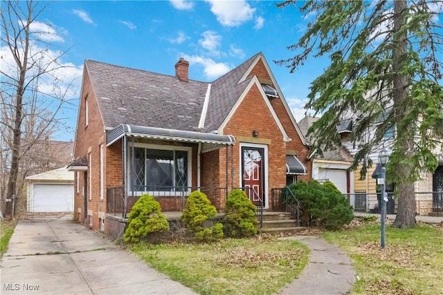 tudor-style house featuring a chimney, brick siding, fence, and a garage