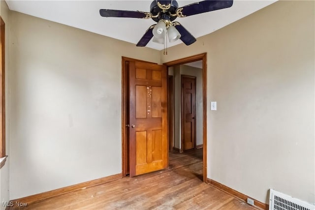 empty room featuring visible vents, light wood finished floors, baseboards, and ceiling fan