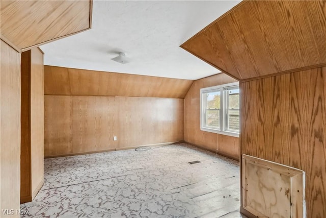 bonus room featuring lofted ceiling, visible vents, and wood walls