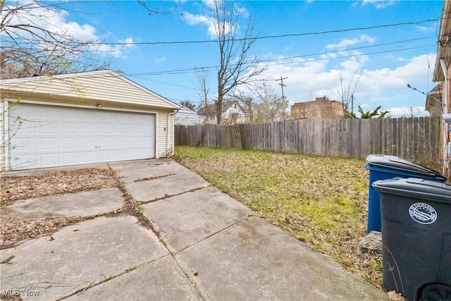 view of yard featuring a detached garage, an outbuilding, and fence