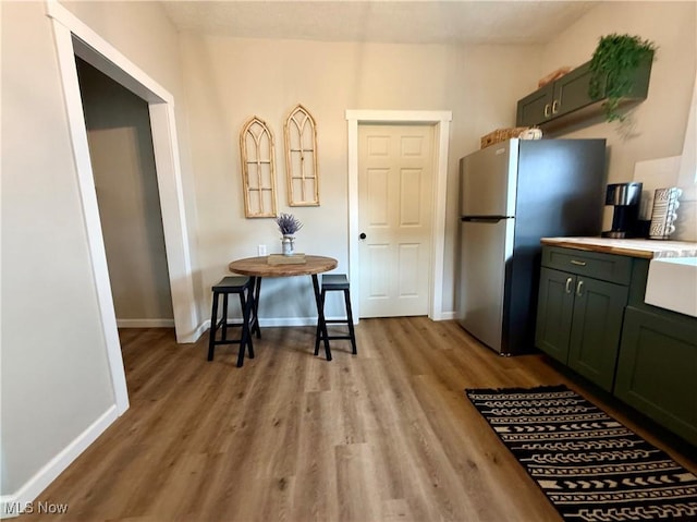 222 Smith St, Niles, OH 44446 - kitchen featuring baseboards, light wood-style flooring, freestanding refrigerator, and green cabinetry