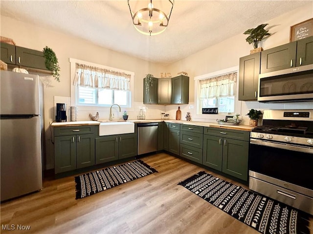 222 Smith St, Niles, OH 44446 - kitchen featuring a sink, green cabinets, stainless steel appliances, light countertops, and backsplash