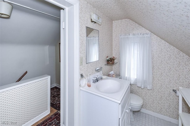 bathroom featuring vaulted ceiling, toilet, vanity, and baseboards