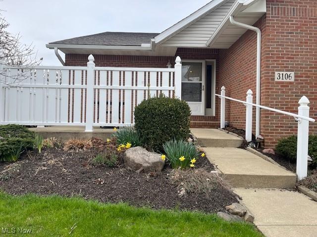 doorway to property with brick siding and fence