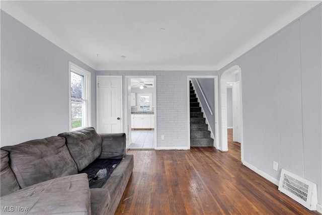living area with stairs, hardwood / wood-style flooring, arched walkways, baseboards, and visible vents