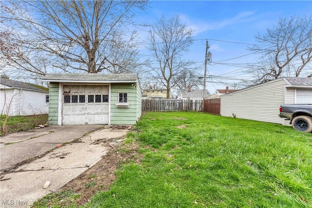 view of yard with fence, driveway, an outbuilding, and a detached garage
