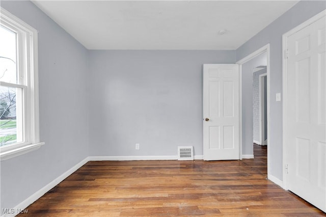 unfurnished bedroom featuring wood finished floors, visible vents, and baseboards