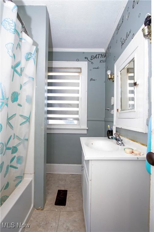 bathroom with tile patterned floors, shower / bath combo with shower curtain, vanity, and crown molding