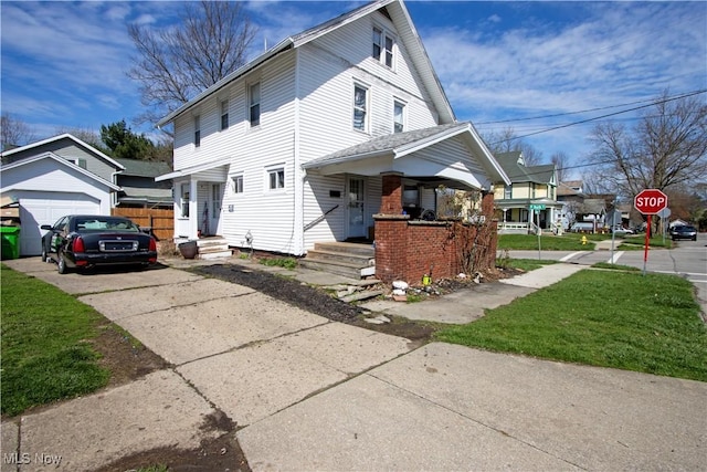 view of front of property featuring a garage, a front lawn, concrete driveway, and covered porch