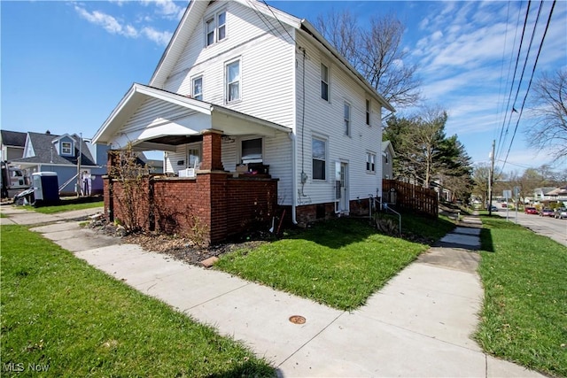 view of property exterior with a residential view, a porch, and a yard