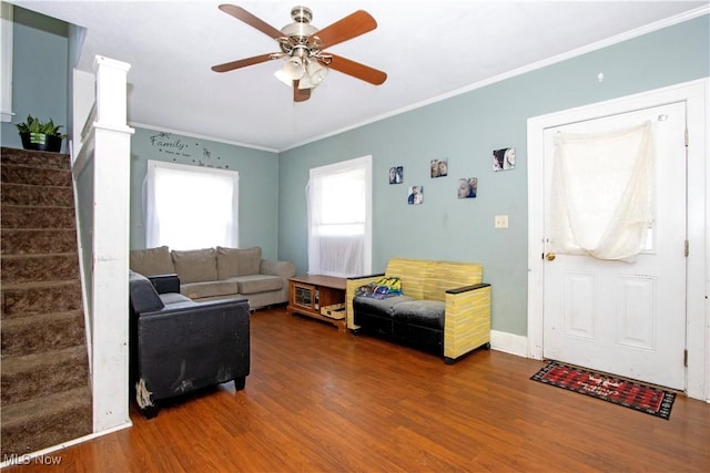 living area featuring baseboards, wood finished floors, ceiling fan, stairway, and ornamental molding