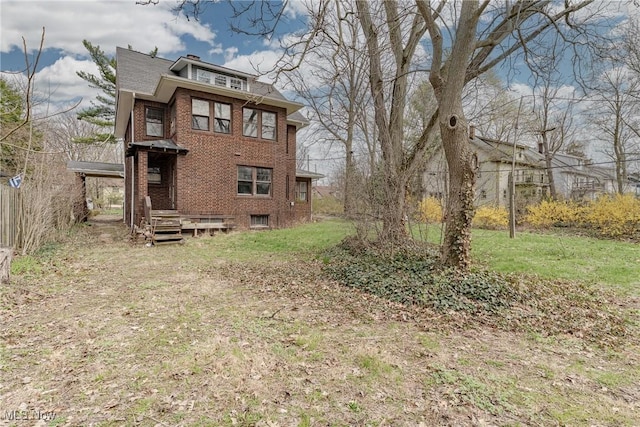 back of property featuring a lawn and brick siding