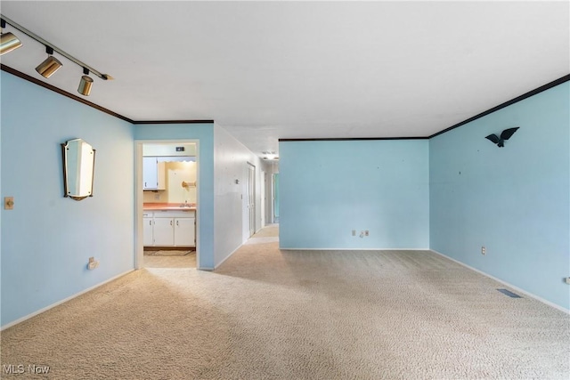 unfurnished living room featuring visible vents, baseboards, light colored carpet, and crown molding
