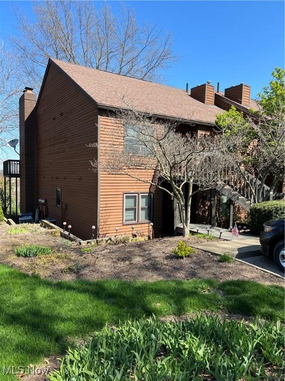 view of side of home with a shingled roof and a chimney