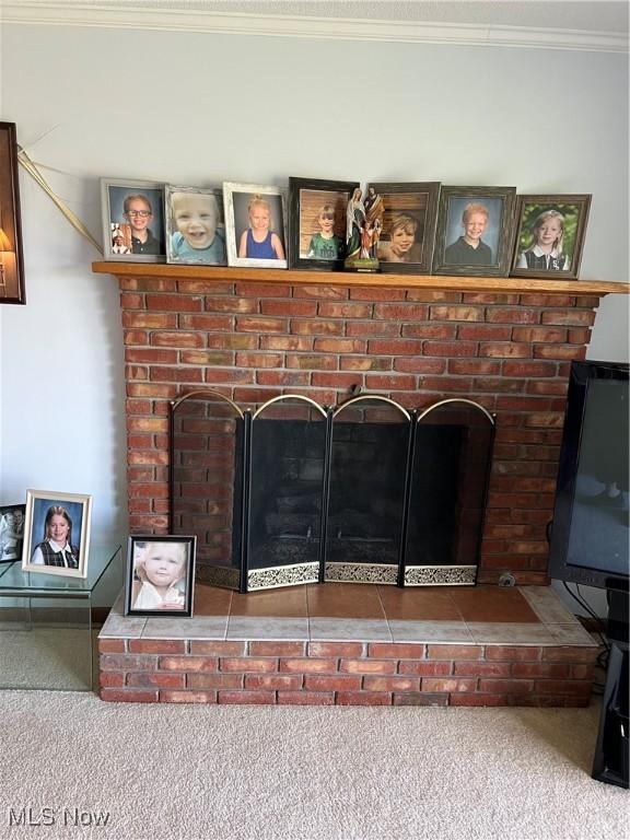 room details with carpet flooring, ornamental molding, and a brick fireplace
