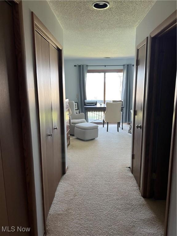 hallway with carpet and a textured ceiling