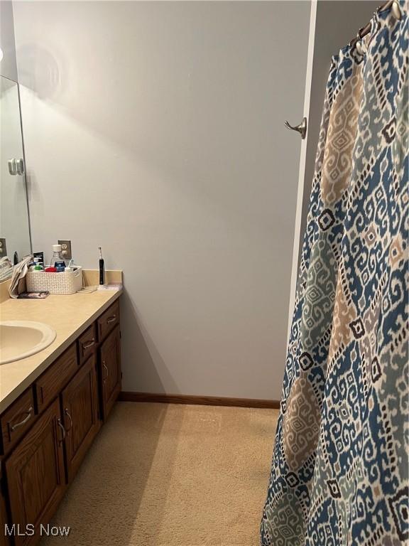 bathroom with baseboards, vanity, and curtained shower