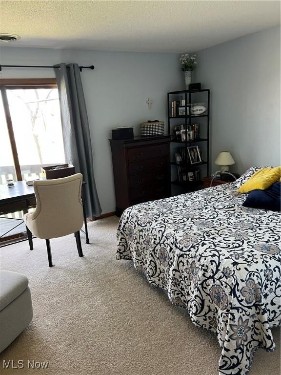 bedroom featuring a textured ceiling, carpet floors, and visible vents