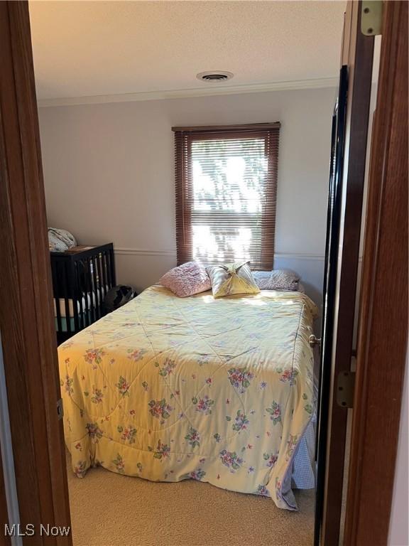 bedroom featuring ornamental molding, carpet flooring, and visible vents