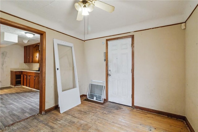 empty room with baseboards, a ceiling fan, and light wood-style flooring