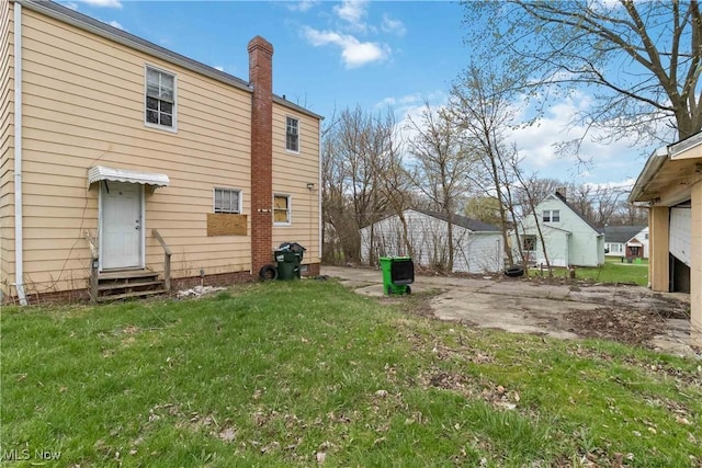 rear view of property with a yard, entry steps, and a chimney