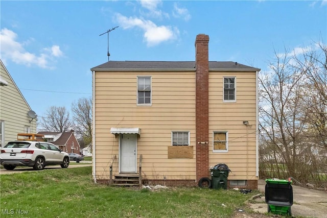 back of house with a lawn, a chimney, and entry steps