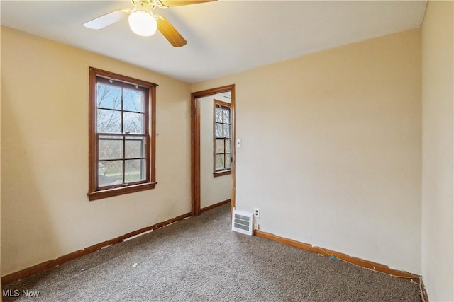 carpeted empty room with visible vents, baseboards, and ceiling fan