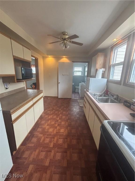 405 Oak Knoll Ave SE, Warren, OH 44483 - kitchen with a sink, black microwave, ceiling fan, white cabinetry, and stove