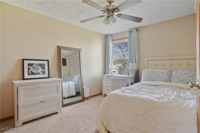 bedroom with light colored carpet, ceiling fan, baseboards, and a textured ceiling